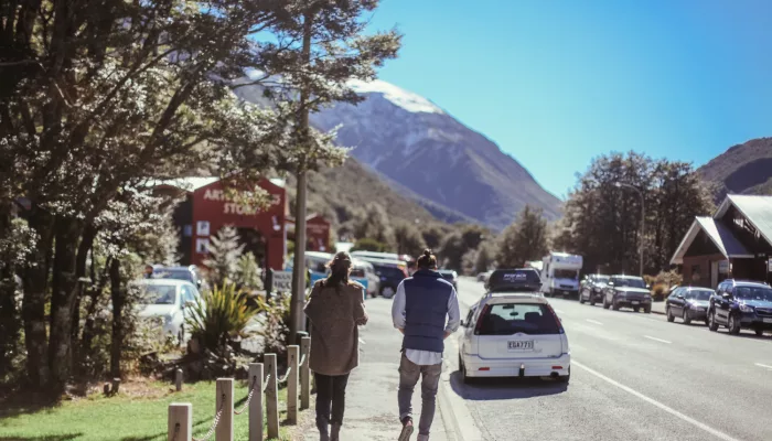 Tourists walking through Arthur’s Pass village with mountains in the background