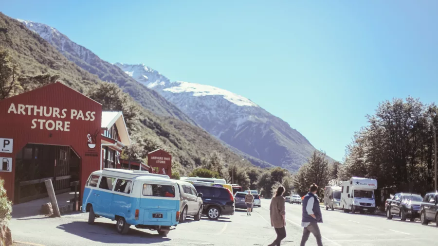 Arthur’s Pass village store with visitors and a snowy mountain backdrop