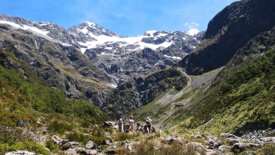 Hikers exploring the rocky trail in Upper Bealey Valley surrounded by snow-capped peaks