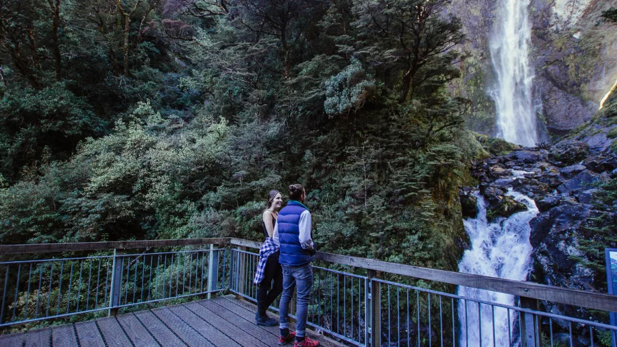 Couple enjoying the view from Devil’s Punchbowl lookout at Arthur’s Pass waterfall