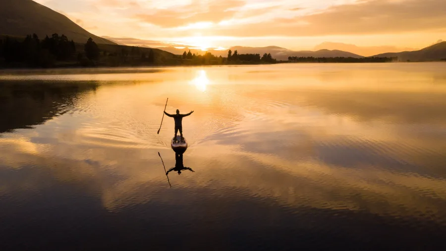 Person paddleboarding on Lake Camp at sunset, Ashburton Lakes, New Zealand