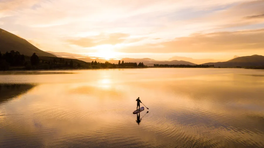 Paddleboarder at sunset on Ōtautari (Lake Camp), Ashburton Lakes, Mid Canterbury, New Zealand