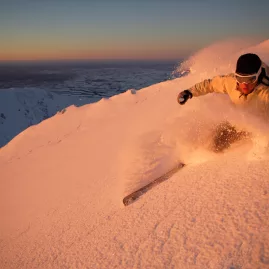 Skier carving powder at sunrise on Mt Hutt slopes