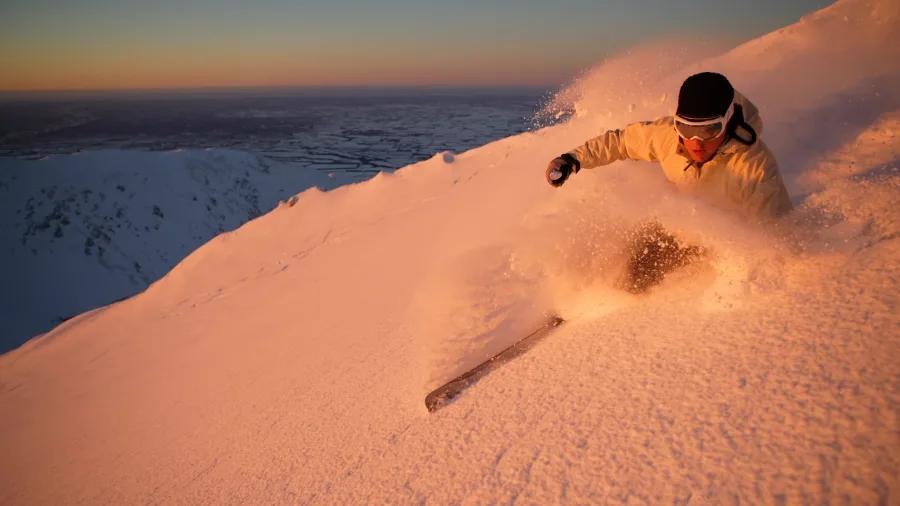Skier carving powder at sunrise on Mt Hutt slopes