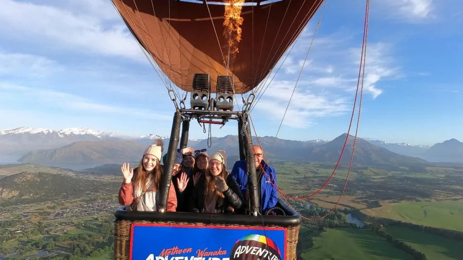 Hot air balloon in flight with burner flame over Wanaka