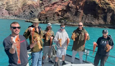 Group holding freshly caught crayfish and red gurnard aboard a fishing charter in Akaroa
