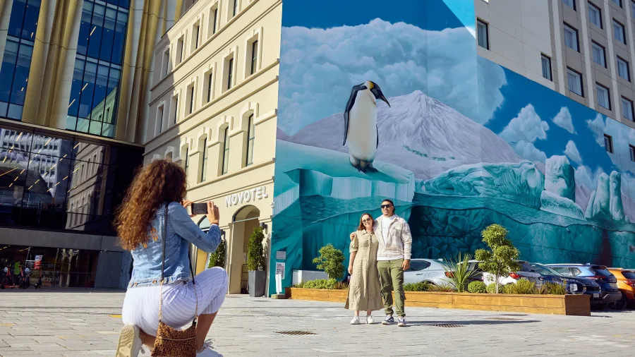Tourists posing in front of Antarctic mural at Cathedral Square, Christchurch