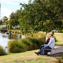 Couple sitting beside the Avon River in Hagley Park, Christchurch