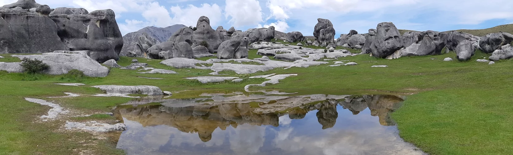 Castle Hill rock formations reflected in a shallow pool under a moody sky