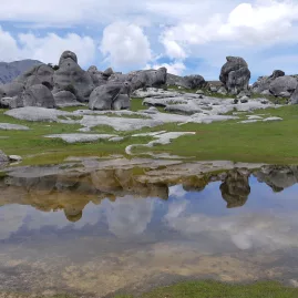 Limestone boulders at Castle Hill reflecting in a shallow pool under a bright sky in Canterbury, New Zealand