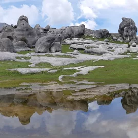 Castle Hill rock formations reflected in a shallow pool under a moody sky