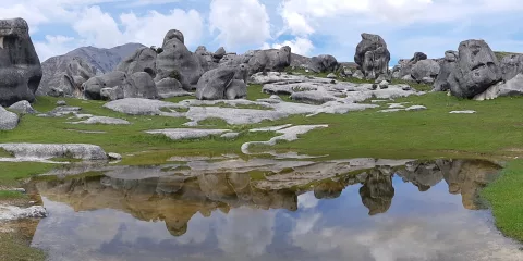 Castle Hill rock formations reflected in a shallow pool under a moody sky