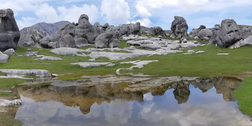 Castle Hill rock formations reflected in a shallow pool under a moody sky