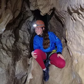 Explorer navigating narrow limestone passage in Cave Stream