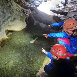 Children pointing at clear stream water inside Cave Stream cave system