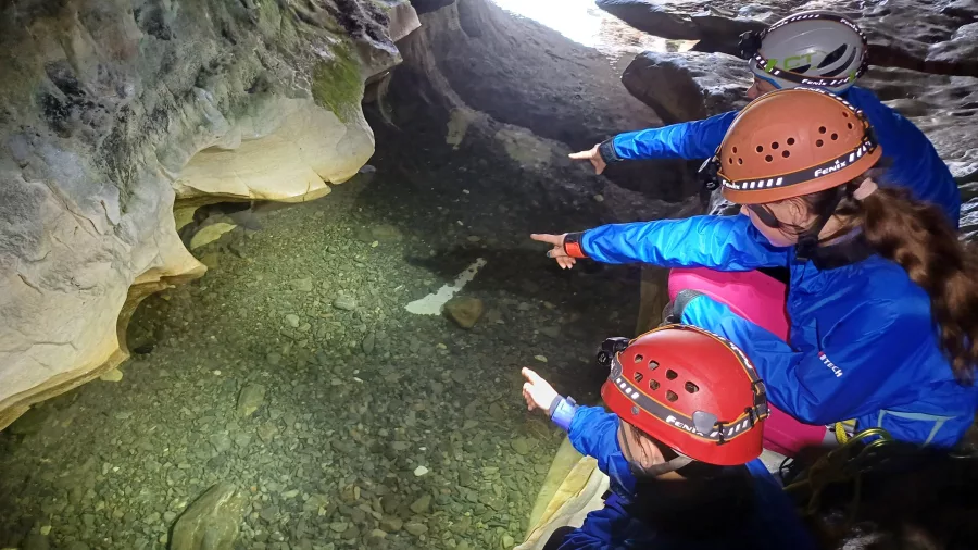 Children pointing at clear stream water inside Cave Stream cave system