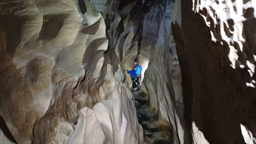 Person walking through narrow limestone cave passage in Cave Stream