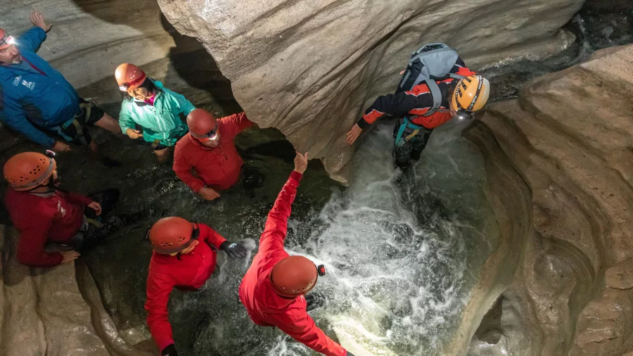 Group with helmets exploring limestone cave formations inside Cave Stream