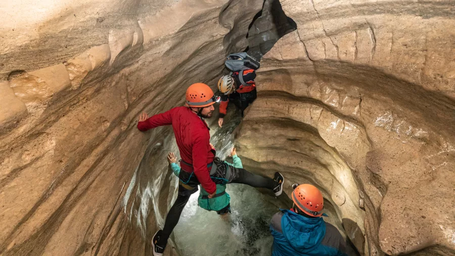 Climbers navigating steep limestone walls inside a narrow section of Cave Stream