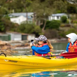Two people kayaking near Quail Island, one taking a photo