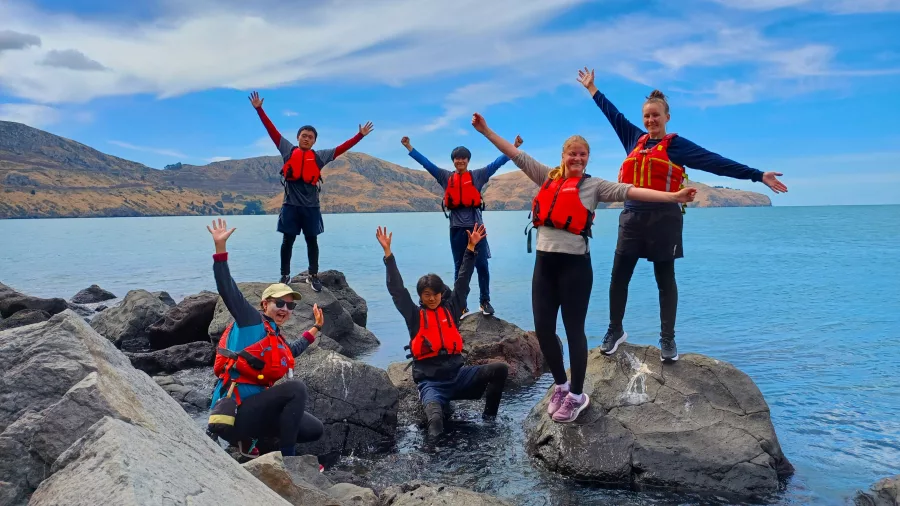 Group of kayakers posing on rocks near Quail Island, Lyttelton Harbour