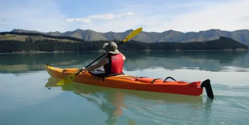Person kayaking solo on calm turquoise water near Quail Island