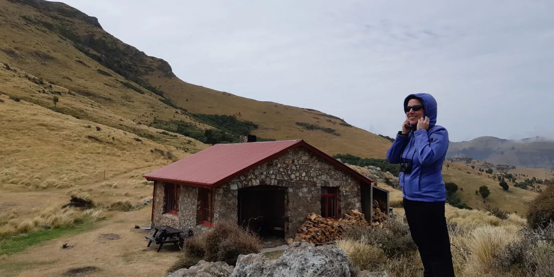 Female hiker standing near Packhorse Hut in Canterbury’s tussock-covered hills