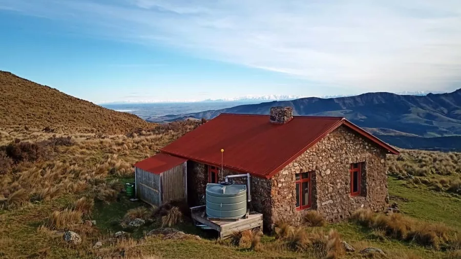 Historic stone Packhorse Hut with red roof above Lyttelton Harbour on Banks Peninsula