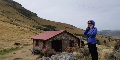 Female hiker standing near Packhorse Hut in Canterbury’s tussock-covered hills