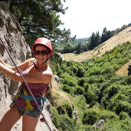 Woman enjoying her first rock climbing experience with lush hills in the background