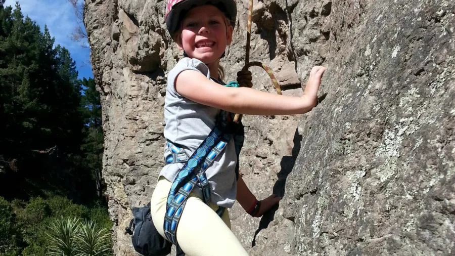 Child smiling while rock climbing on the Port Hills near Christchurch
