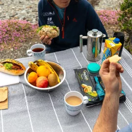 Outdoor picnic break with fruit, tea, and wraps on a striped tablecloth