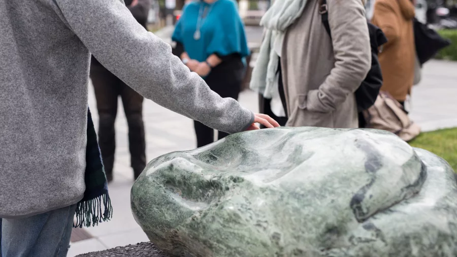Visitor touching a greenstone sculpture during a Māori cultural walking tour with Amiki in Christchurch