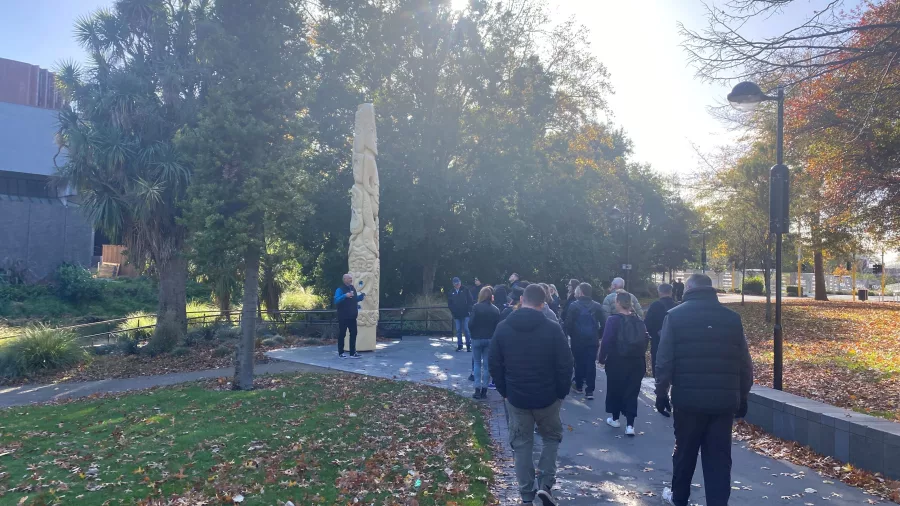 Amiki Tours group walking past the carved pou in Victoria Square, formerly known as Market Square in Christchurch