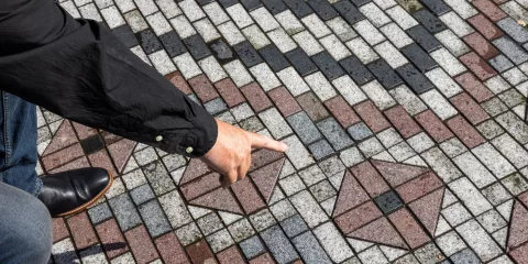 Guide pointing to a whāriki paving design symbolising traditional Māori weaving