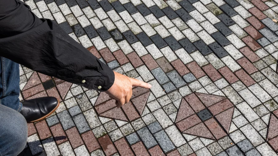 Guide pointing to a whāriki paving design symbolising traditional Māori weaving