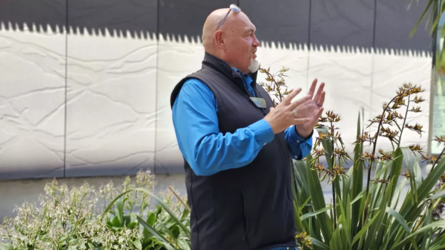 Tour guide speaking in front of the Waimakariri mural outside Tūranga Library