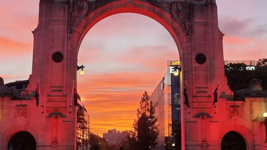 Bridge of Remembrance in Christchurch glowing pink under a dramatic sunset sky
