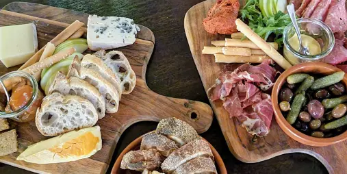 Charcuterie and cheese platter with cured meats, pickles, olives, bread, and spreads