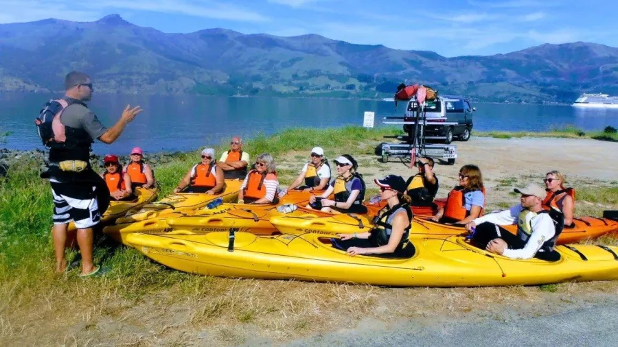 Kayak guide giving a safety briefing to a group of paddlers before launching in Akaroa