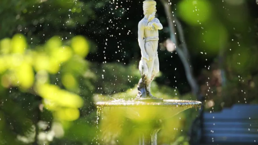 Decorative garden fountain with a classical statue surrounded by lush greenery