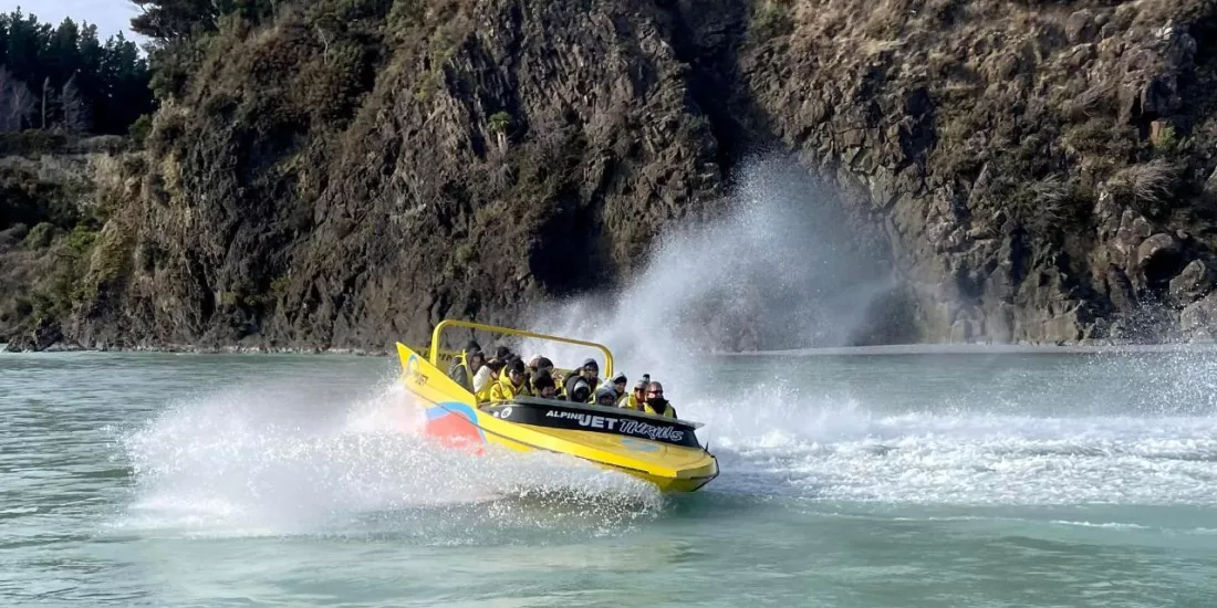 Jet boat speeding through the turquoise waters of Waimakariri Gorge near Christchurch