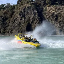 Jet boat speeding through the turquoise waters of Waimakariri Gorge near Christchurch