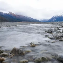 Shallow waters of the Waimakariri River with snow-capped mountains in the distance