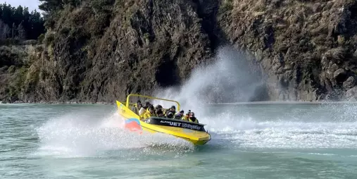 Jet boat speeding through the turquoise waters of Waimakariri Gorge near Christchurch