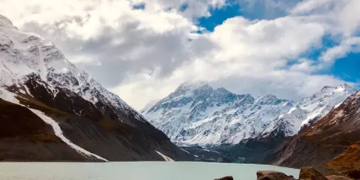 Snow-covered mountains reflecting in Hooker Lake at Aoraki Mount Cook National Park