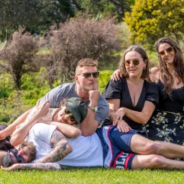Friends relaxing on the lawn with glasses of wine in Waipara Valley.