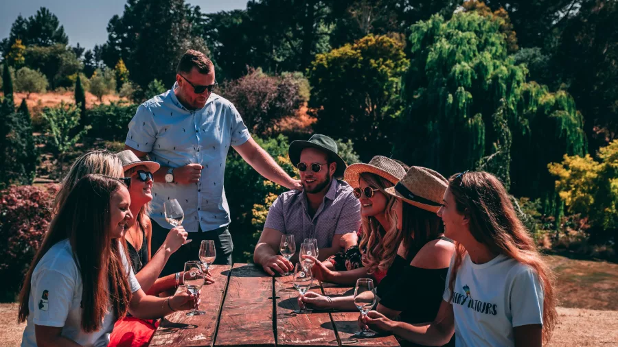 Tour group enjoying a wine tasting at a picnic table in Waipara Valley.