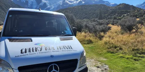 Cheeky Kea Travel van parked in front of the Southern Alps on a scenic South Island tour