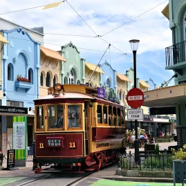 Red Christchurch Tram leaving New Regent Street past pastel-coloured shops